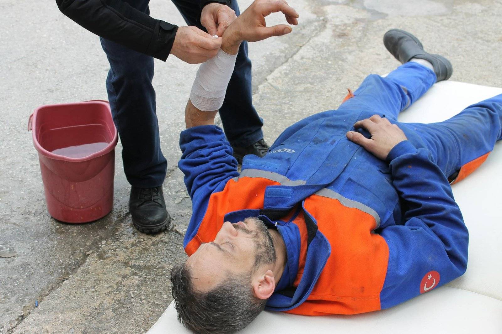 injured man lying on the ground receving a first aid treatment